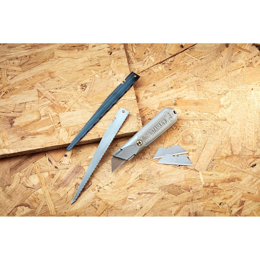 STANLEY 0-10-129 folding utility knife with blade, saw blade, cover, and spare blades on wood surface.
