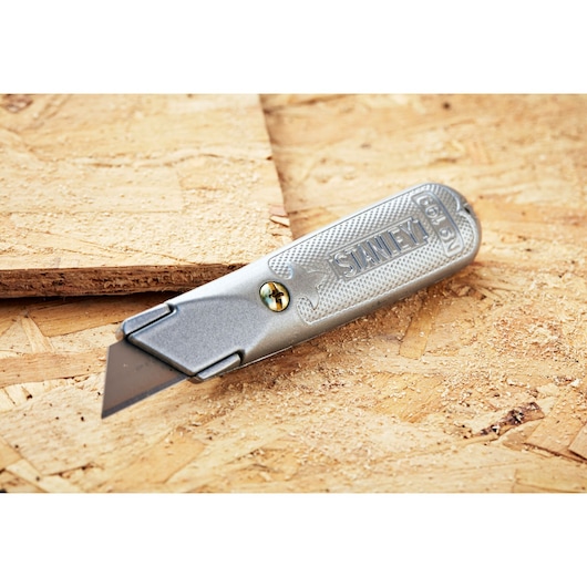 STANLEY 0-10-129 utility knife with metal handle, silver finish, shown on plywood surface.