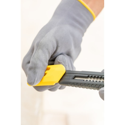 STANLEY 0-10-151 utility knife with yellow slider held by gloved hand, close-up side view.