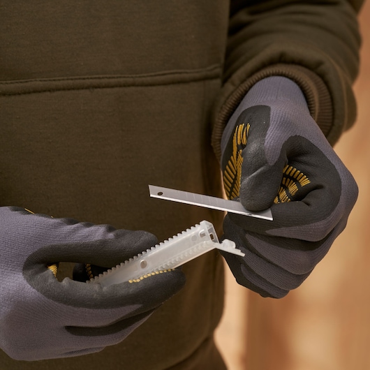 STANLEY 0-11-300 utility knife blade held by gloved hands, close-up photography.