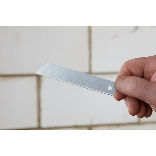 Photo of STANLEY 0-11-301 snap-off utility knife blade held in hand, silver with scored sections.