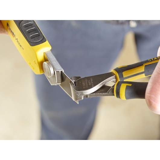 STANLEY 0-11-725 utility knife with yellow and black handle being cut by STANLEY pliers in close-up.
