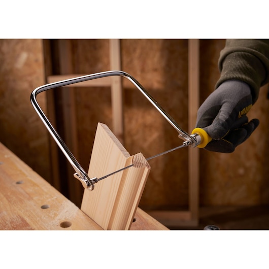 STANLEY 0-15-106 coping saw used to cut wood, close-up photography in workshop setting.