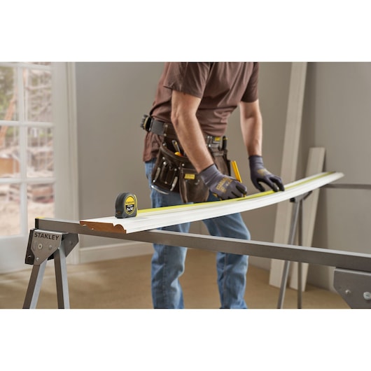 STANLEY 0-30-686 tape measure on a workbench during woodworking, person wearing gloves marking wood.