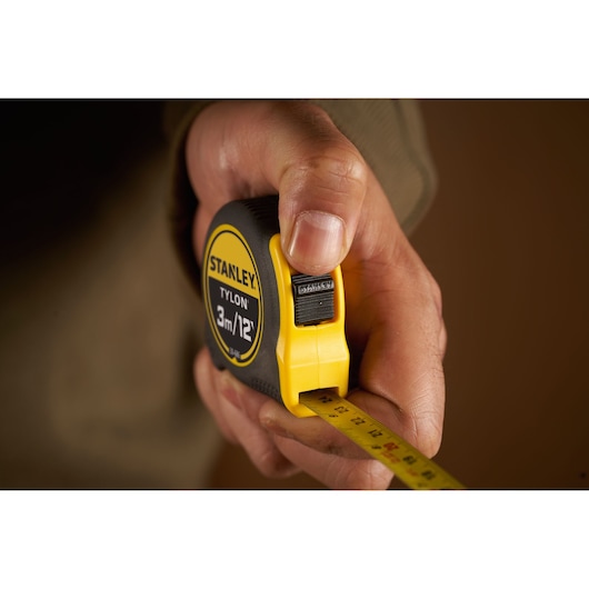 Photo of STANLEY 0-30-686 tape measure held in hand, yellow and black casing, extended measuring tape.