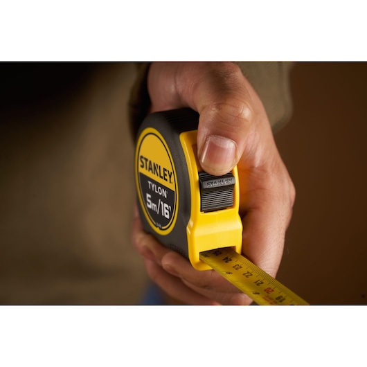 Photo of STANLEY 0-30-696 tape measure Tylon 5m/16ft held in hand, yellow and black exterior.