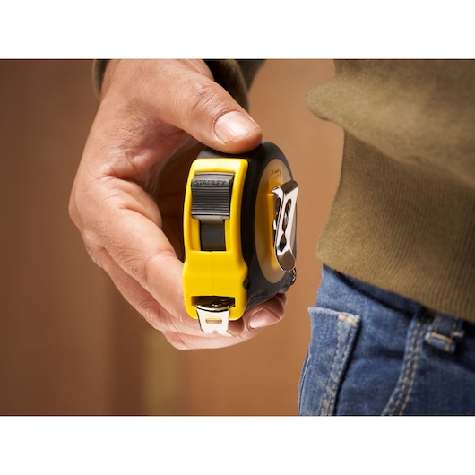Stanley 0-30-696 tape measure in hand, close-up, yellow and black case with belt clip.