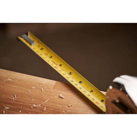 STANLEY 0-33-526 tape measure extended over wooden board with wood shavings, close-up photography.