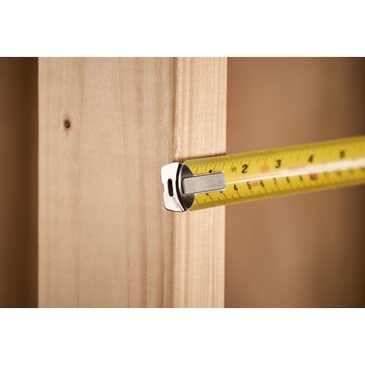 STANLEY 0-33-526 tape measure in use measuring wood, close-up side view.