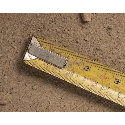 STANLEY 0-33-526 yellow tape measure with metal clip, close-up on dirt, numbers and markings visible.