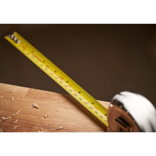 STANLEY 0-33-553 tape measure extended on wood surface with wood shavings, close-up angle.