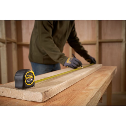 STANLEY 0-33-719 tape measure on wood, person marking plank in workshop.