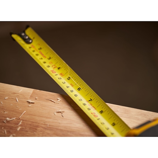 STANLEY 0-33-719 tape measure close-up, yellow blade with black markings, measuring wood, photography.