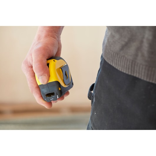 STANLEY 0-33-728 tape measure in hand, yellow and black, close-up photography.
