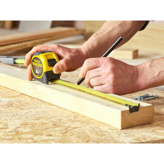 Stanley 0-33-728 tape measure in use on wood, yellow and black, photography of marking measurements.