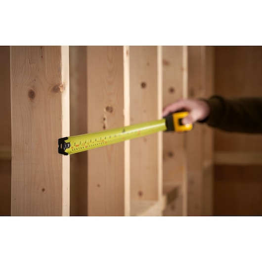 STANLEY 0-33-805 tape measure photography, measuring wooden studs in construction setting.