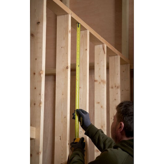 STANLEY 0-33-805 tape measure used to measure wooden studs during construction.