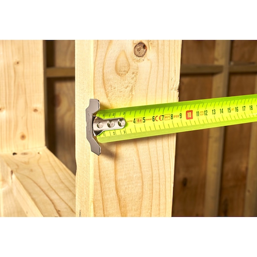 STANLEY 0-33-892 tape measure shown measuring a wooden beam, close-up side angle.