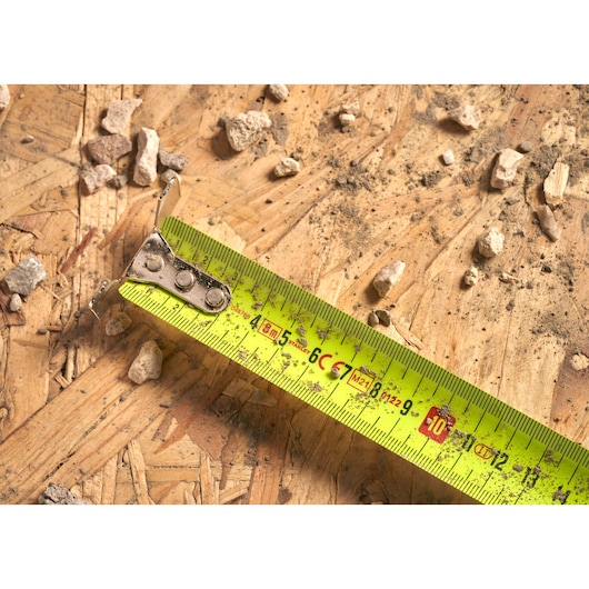 STANLEY 0-33-892 yellow tape measure on wood with debris, close-up view, photography product category.