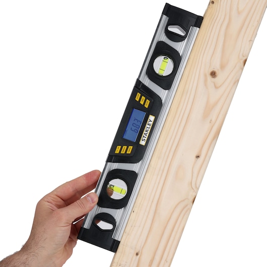 Photo of STANLEY 0-42-063 digital spirit level with LCD display, shown measuring angle on wood plank.