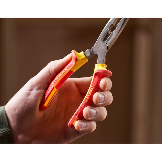 Stanley 0-84-008 insulated pliers with red and yellow handles held in hand, close-up view.