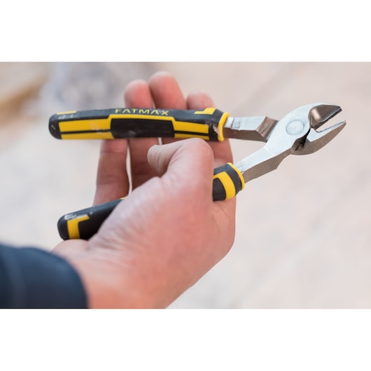 STANLEY 0-89-860 diagonal cutting pliers with black and yellow handle held in hand, side angle.