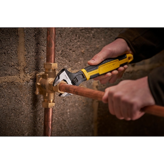 STANLEY 0-90-947 adjustable wrench used on copper pipe fitting, close-up indoor photography.