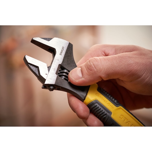 STANLEY 0-90-947 adjustable wrench with yellow and black handle held in hand, close-up photography.