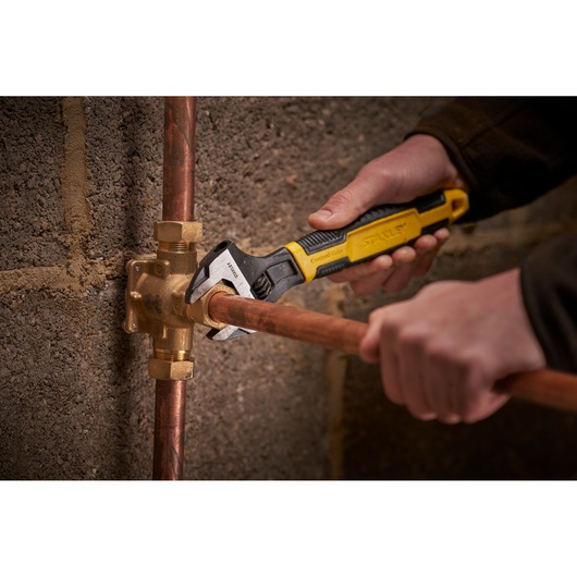 STANLEY 0-90-949 adjustable wrench used on copper pipe fitting, close-up photography.