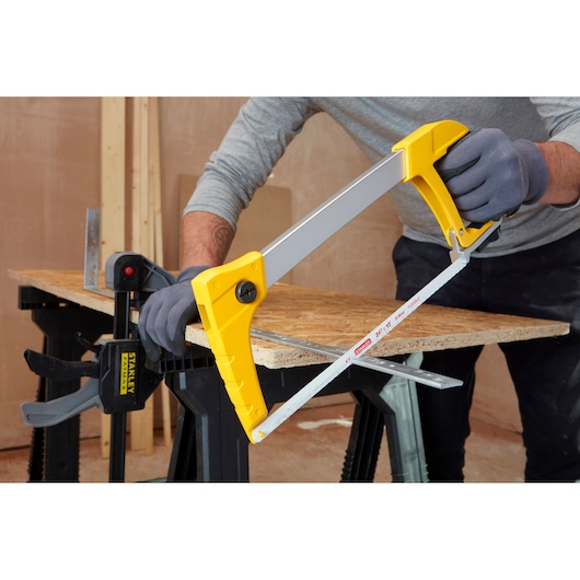 STANLEY 1-20-110 hacksaw with yellow handle cutting metal on workbench, photography of tool in use.