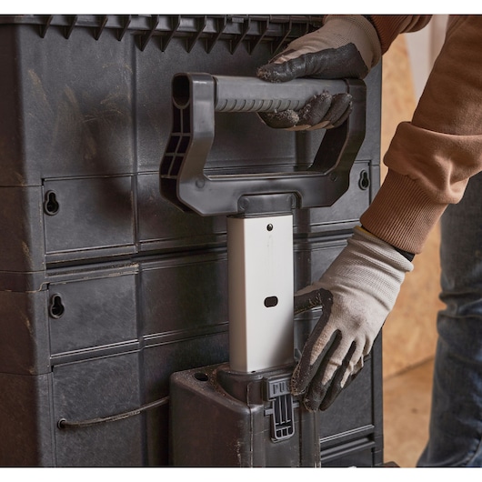 Photo of STANLEY 1-79-206 tool box trolley handle being extended by a gloved hand.