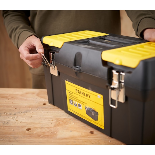 STANLEY 1-92-066 tool box with yellow lid and metal latches, front angle, on wooden table.