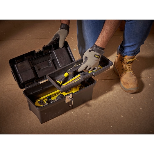 STANLEY 1-94-857 black toolbox opened with tools, person wearing gloves and boots holding tray.