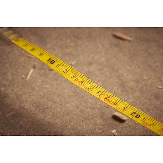 STANLEY 2-34-777 yellow measuring tape close-up on textured ground, photography