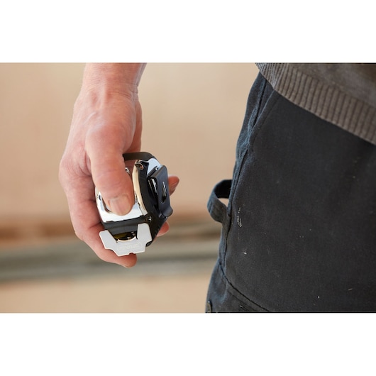 Stanley 5-33-886 tape measure held in hand close-up, black and silver finish, photography product.