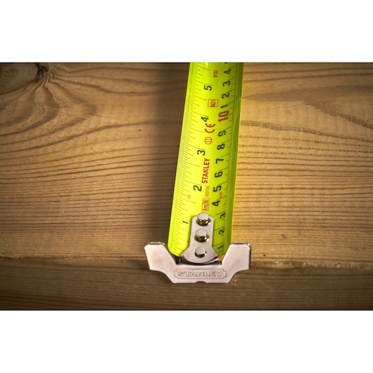 STANLEY 5-33-891 tape measure close-up, yellow blade measuring wooden plank, top view.