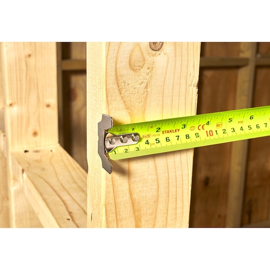 Photo of STANLEY 5-33-891 tape measure extended across wooden beams, close-up view.
