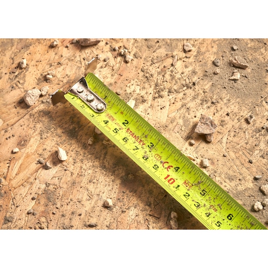 Photo of STANLEY 5-33-891 tape measure with yellow blade on a dusty wooden surface with small debris.