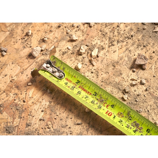 STANLEY 5-33-896 tape measure photography on dusty wood surface with debris, close-up angle.