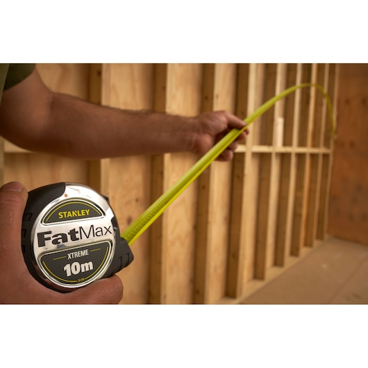 Photo of STANLEY FatMax 10m tape measure, SKU 5-33-896, used for measuring wooden frame.
