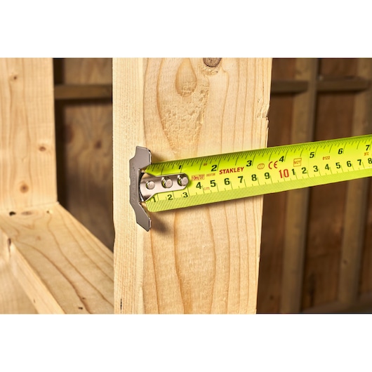 Stanley 5-33-896 tape measure measuring wooden beam, photography side angle.
