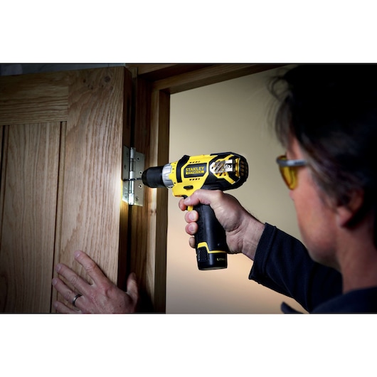 Photo of STANLEY FMC010LB cordless drill used to install a hinge on a wooden door.