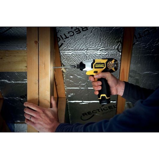 Photo of STANLEY FMC040LB cordless drill driver in use driving screw into timber frame, close-up view.