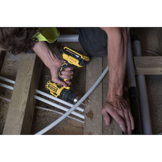 STANLEY FMC607D2 drill used on wooden beams in construction, close-up photography of hand holding tool.