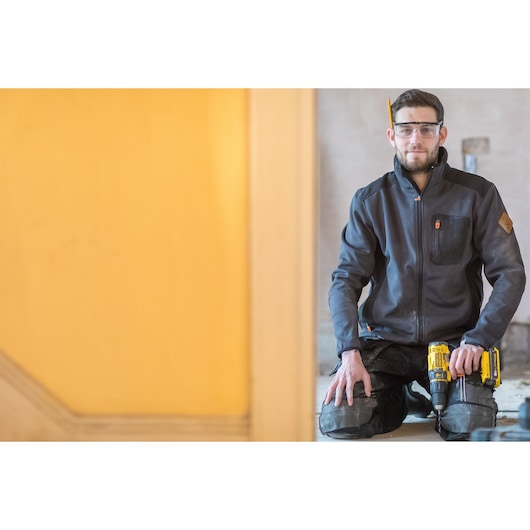 Photo of worker kneeling holding STANLEY FMC626C2K cordless drill in construction setting.