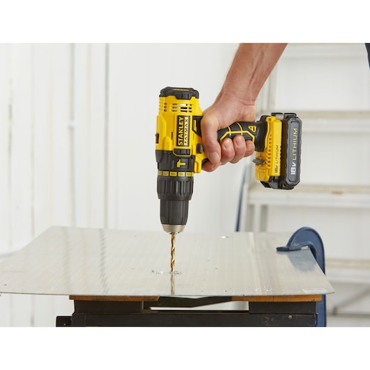 Photo of STANLEY FMC626C2K cordless drill in use drilling metal sheet, side angle.
