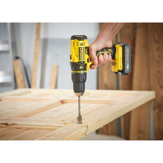 STANLEY FMC626C2K cordless drill with 18V lithium battery drilling into wood, close-up side angle.