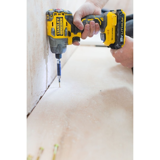 STANLEY FMC647B cordless impact driver in use, close-up side view, yellow and black.