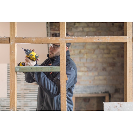 STANLEY FMC647B cordless drill in use on wooden frame, side view.
