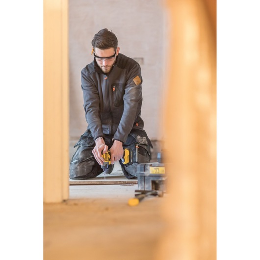 Photography of STANLEY FMC647B cordless drill in use by worker on construction site, indoor scene.